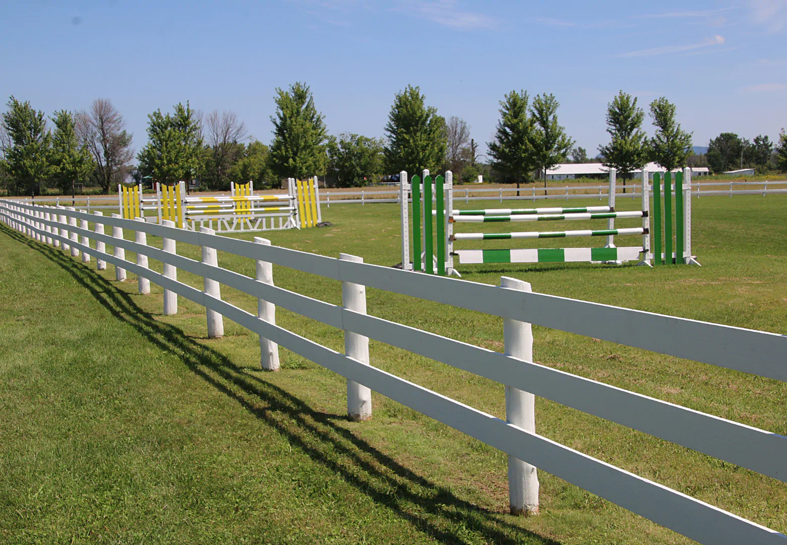 white horse fence at the side of an obstacle course
